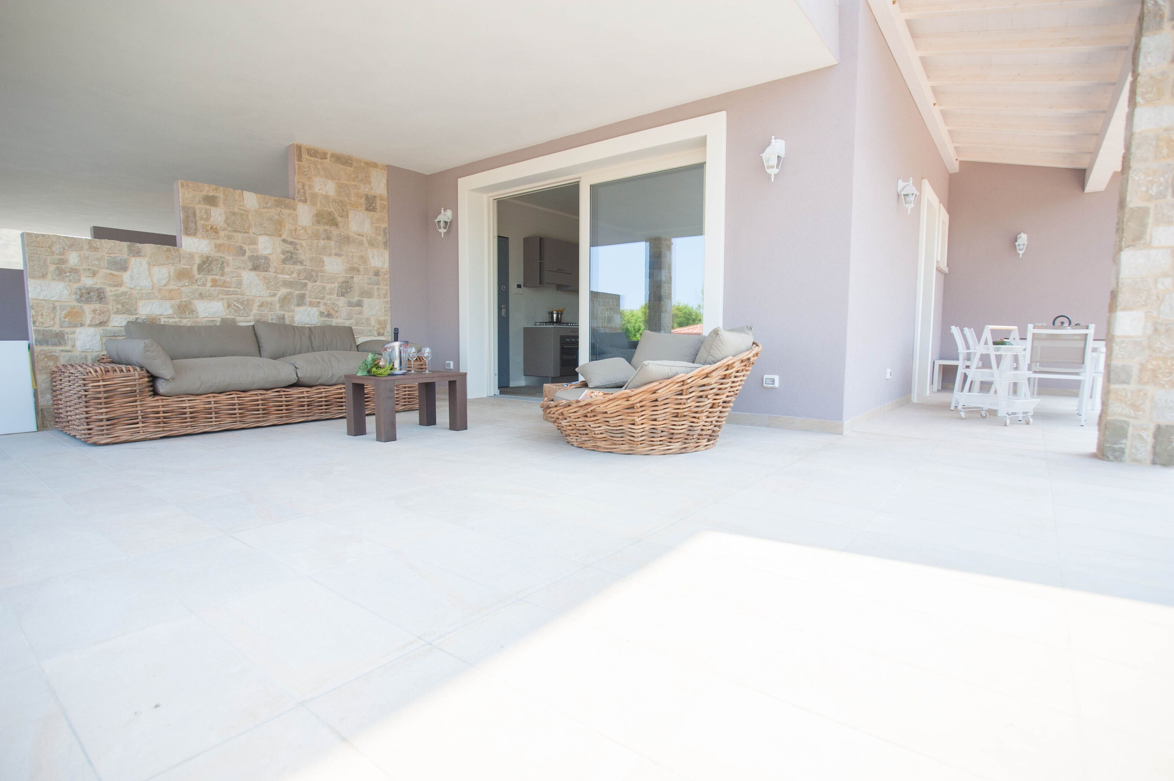 Un patio amplio con mobiliario de mimbre, una zona de comedor y vistas a la cocina.