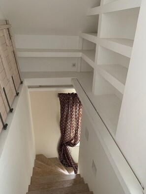 Staircase leads to a landing area with a shelf.