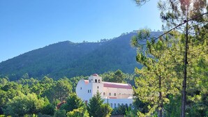 A white building with a red roof surrounded by dense green trees and a hill in the background. - MINI VILLA 60m² with swimming pool - 2 bedrooms - air-conditioned - terrace - beach 5 mins (Travo VENTISERI)