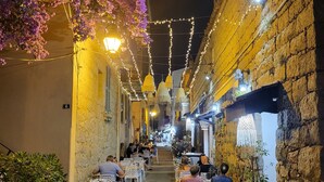 A narrow street with outdoor seating, stone walls, and hanging lights. - MINI VILLA 60m² with swimming pool - 2 bedrooms - air-conditioned - terrace - beach 5 mins (Travo VENTISERI)