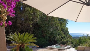 Un área de estar al aire libre con una mesa, sillas y una botella de vino.
