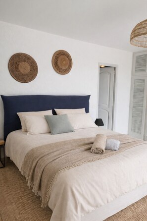 A bedroom with a bed, pillows, a blanket, two wall decorations, and a door.