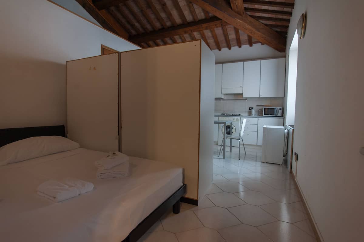 Quarto com cama, guarda-roupa e vista para uma cozinha.