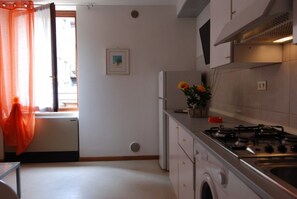 A kitchen with a gas stove, a refrigerator, and a washing machine.