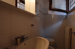 A bathroom with a bathtub, toilet, and a window.