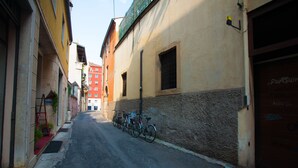 En smal gade med bygninger langs begge sider, cykler parkeret ved fortovet, og en rød bygning i baggrunden.