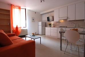 A compact living space with a kitchenette, a dining area, and a seating area with a sofa and chairs.