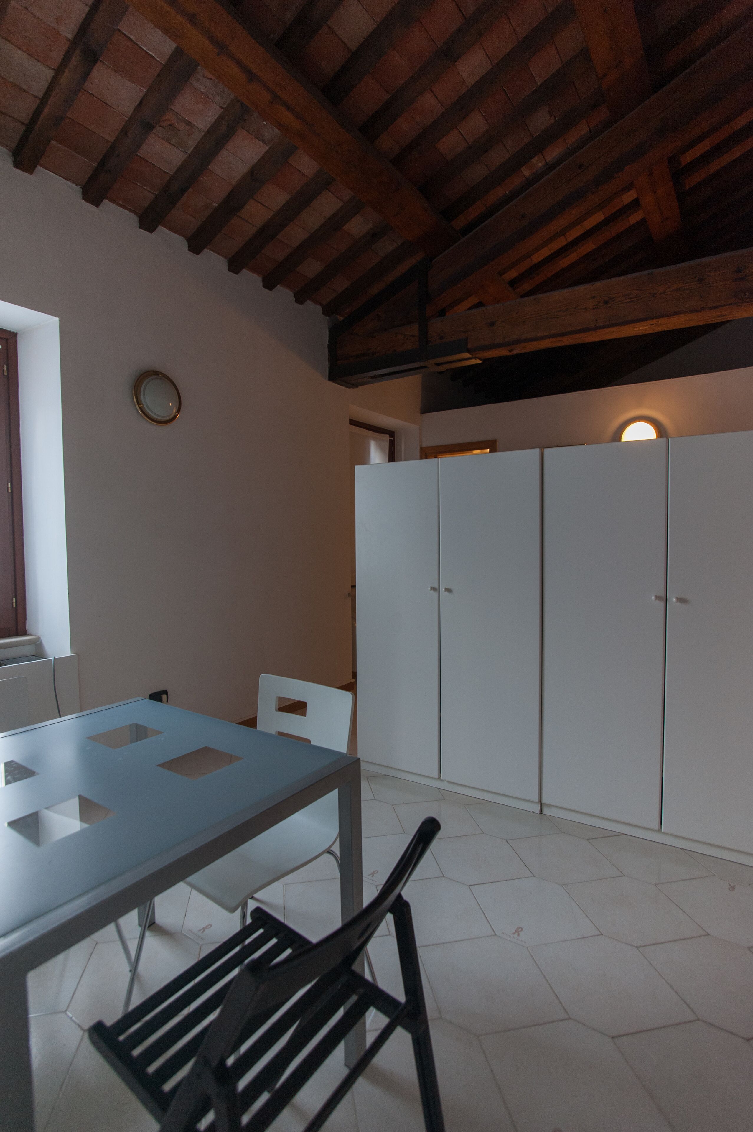 Een keuken met een witte tafel, zwarte stoelen en een houten plafond.