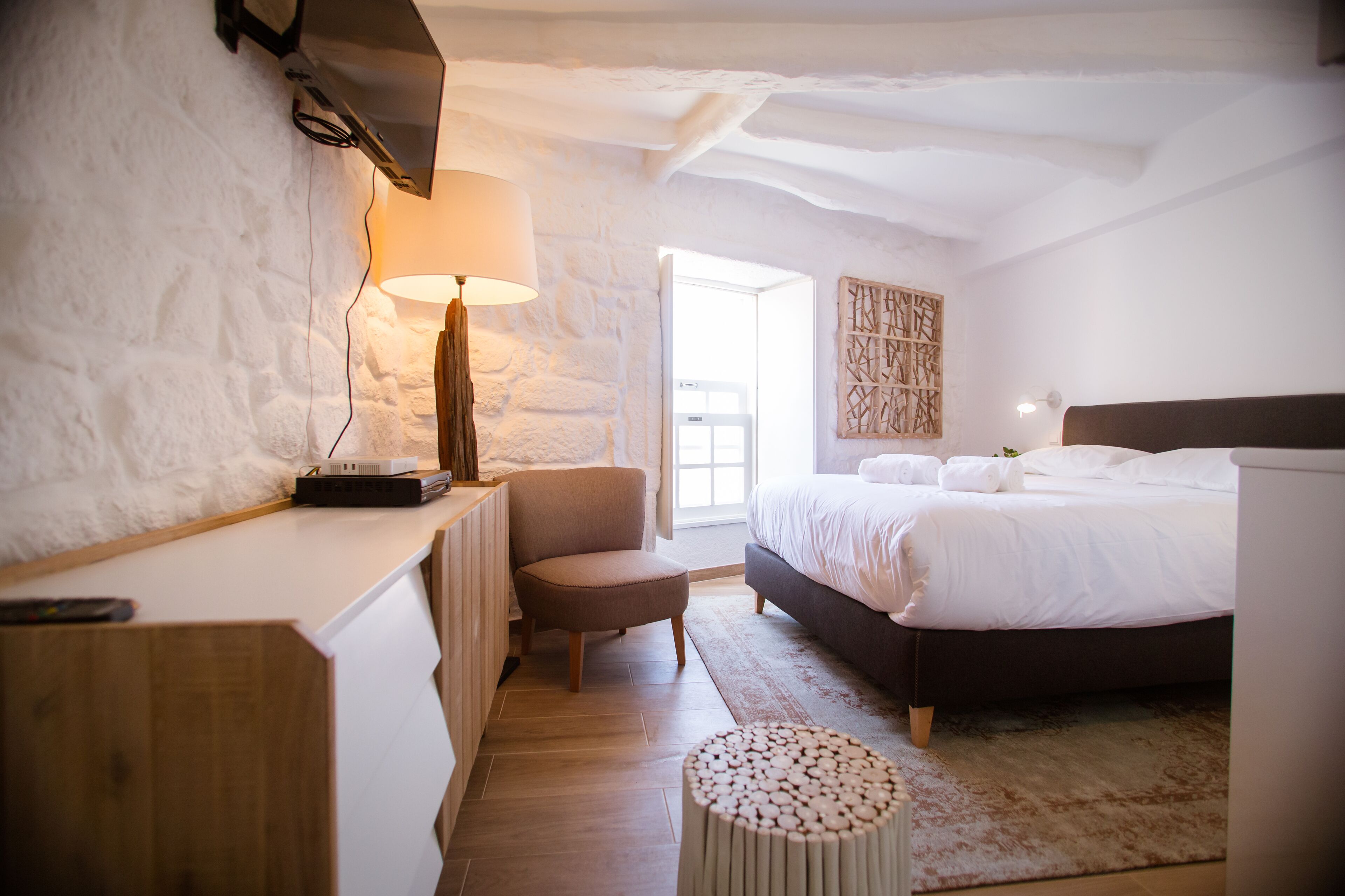 A bedroom with a bed, a desk, a chair, and a lamp.