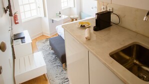 Uma cozinha compacta com pia, bancada pequena e janela com cortinas.