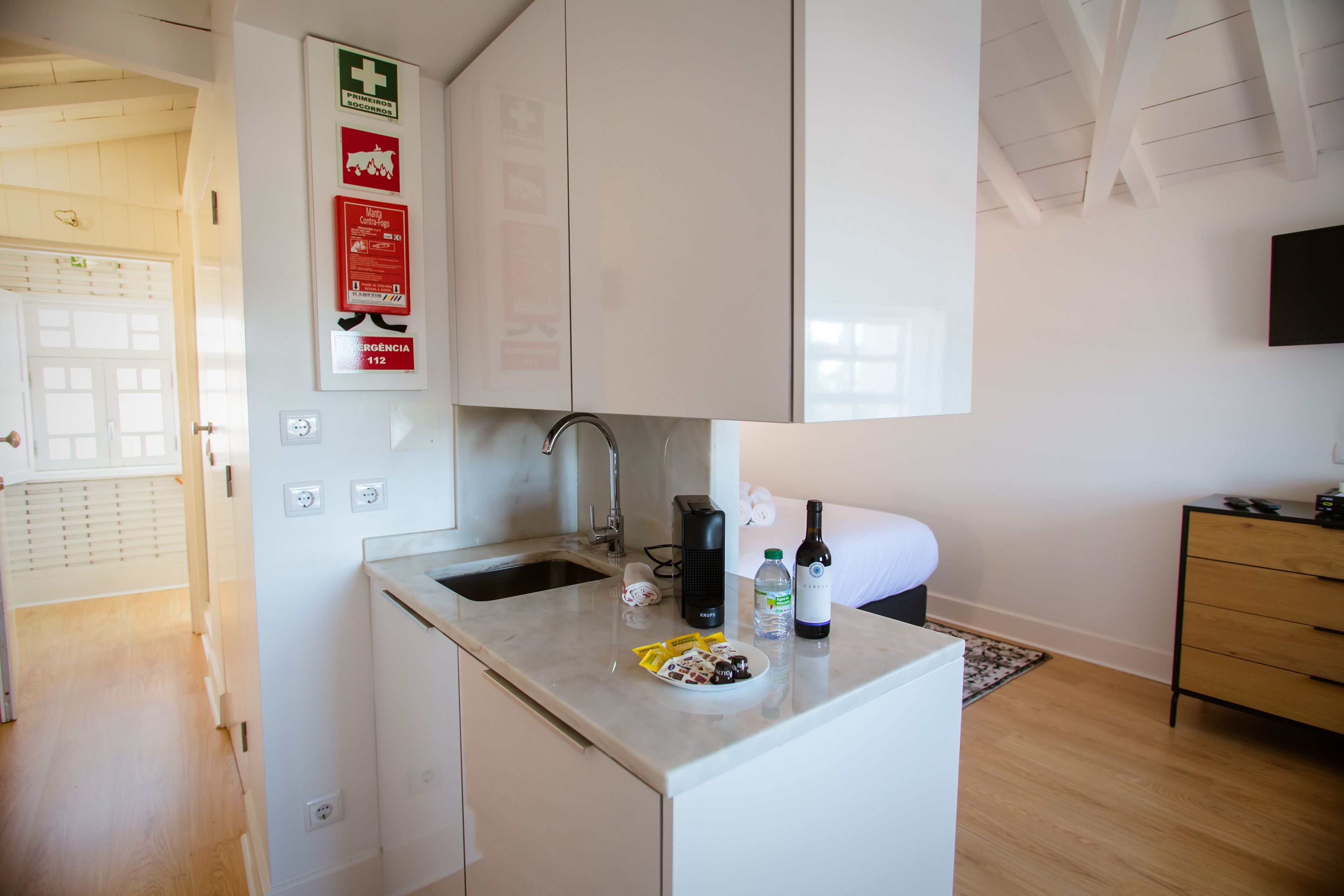 A modern kitchen with white cabinets, a sink, and a countertop with a bottle of wine and a plate of food.