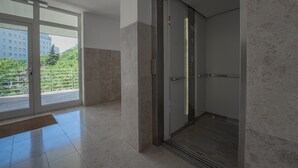 A modern elevator with a glass door, a visible control panel, and a metal handrail. - Sky & Sun Luxury Rooms (Zadar)