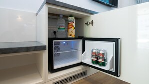 A compact refrigerator with a water bottle and a carton of juice inside. - Sky & Sun Luxury Rooms (Zadar)