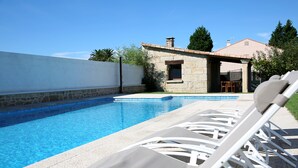 A swimming pool with lounge chairs, a stone building, and a clear sky. - Private house in Viña de Millán (O Grove)