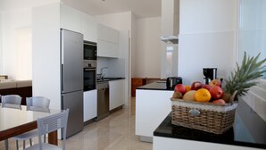 A modern kitchen with white cabinetry, stainless steel appliances, and a dining area with a table and chairs. - Private house in Viña de Millán (O Grove)