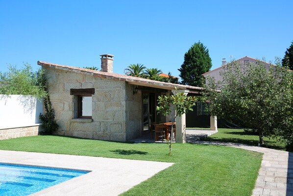 Un bâtiment en pierre avec un toit en tuiles, une piscine et une pelouse bien entretenue.