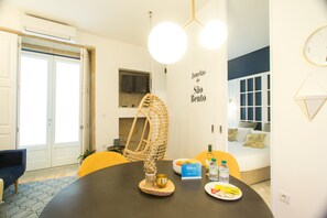 A dining area with a round table, chairs, a hanging light fixture, and a wall-mounted clock. - Janelas de São Bento by Porto City Hosts (Porto)