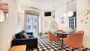 A modern living space with a checkered floor, a sofa, a dining table with chairs, and a hanging chair. - Janelas de São Bento by Porto City Hosts (Porto)