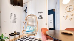 A modern room with a checkered floor, a hanging chair, a round table, and a wall with geometric light fixtures. - Janelas de São Bento by Porto City Hosts (Porto)