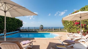 Een buitenzwembad, een verwarmd zwembad, ligstoelen bij het zwembad