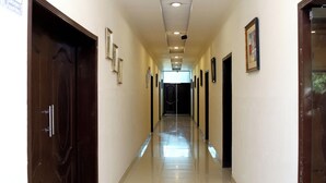 A long, well-lit hallway with doors on both sides, leading to rooms. - Royalton Inn Hotel (Lahore)