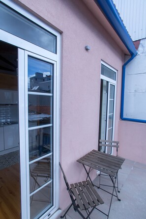A pink building with a large sliding glass door, a small table, and a chair outside. - Picasso Suites Porto by Porto City Hosts (Porto)