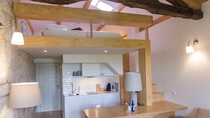 A rustic interior with exposed wooden beams, a kitchen area, and a seating area with a glass table. - Picasso Suites Porto by Porto City Hosts (Porto)