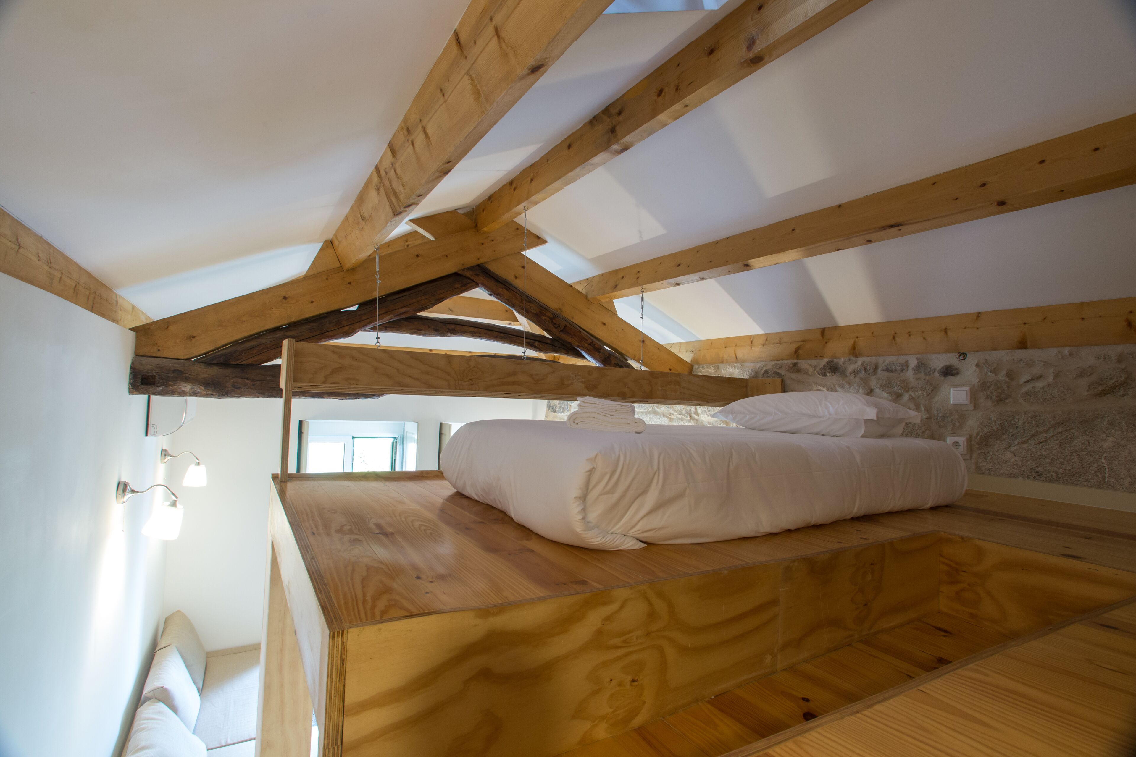 A bedroom with a wooden bunk bed, stone wall, and skylight.