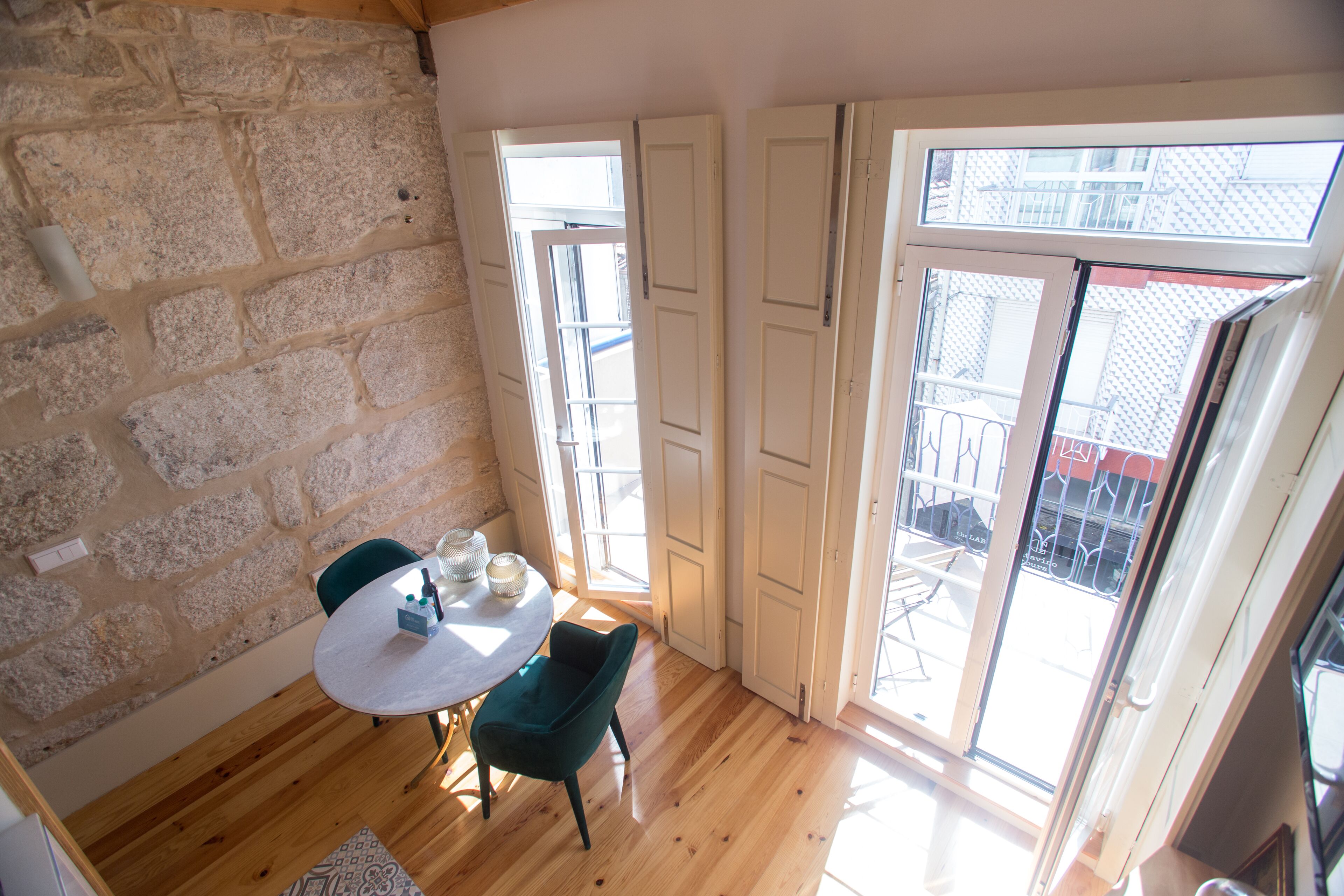 Ein Zimmer mit Steinwand, Holzboden, einem runden Tisch mit Stühlen und einer Schiebeglastür zu einem Außenbereich.
