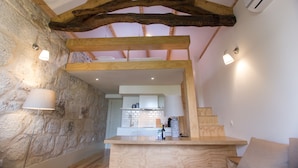 A rustic kitchen with exposed wooden beams, stone walls, and a modern countertop. - Picasso Suites Porto by Porto City Hosts (Porto)
