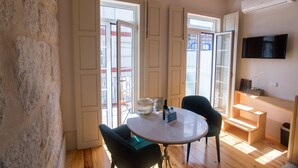 A room with a round table, two chairs, a TV mounted on the wall, and a staircase leading to an upper level. - Picasso Suites Porto by Porto City Hosts (Porto)