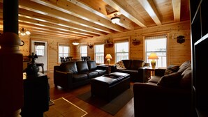 A cozy cabin interior with wooden walls, a fireplace, a sofa, and a dining table.