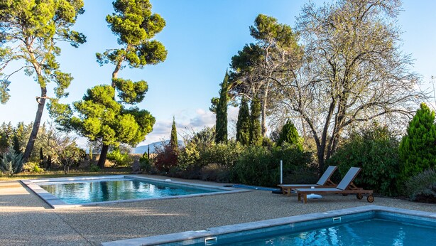 A pool area with two pools, surrounded by trees and a gravel path. - L'Ancien Pigeonnier (Trebes)