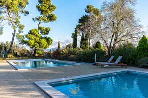 A pool area with two pools, surrounded by trees and a gravel path. - L'Ancien Pigeonnier (Trebes)