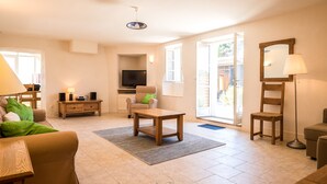 A spacious living room with a sofa, coffee table, TV, and a large window. - L'Ancien Pigeonnier (Trebes)