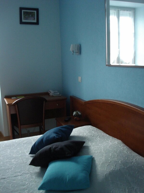 Un dormitorio con una cama, un escritorio y una silla.