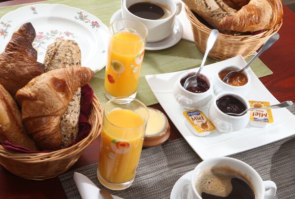 A breakfast setting with croissants, orange juice, coffee, and jam. - Chambres D'hotes La Chaumiere (Arcy-sur-Cure)