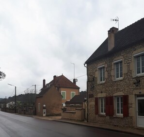 A street view with stone buildings, one with a visible number '5' sign, and a clear road. - Chambres D'hotes La Chaumiere (Arcy-sur-Cure)