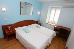 A bedroom with two beds, a desk, a chair, a window with curtains, and a wall-mounted mirror. - Chambres D'hotes La Chaumiere (Arcy-sur-Cure)