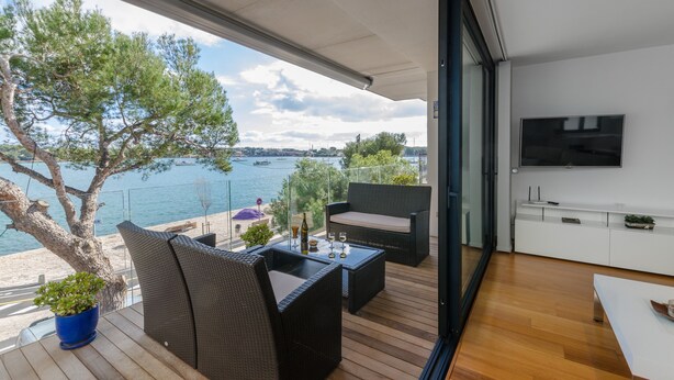 A balcony with wicker furniture, a potted plant, and a view of the sea. - PONENT - Modern apartment with sea views in Portocolom Free WiFi (Portocolom)