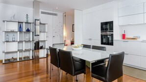 A modern kitchen with white cabinetry, a glass-top dining table, and black chairs. - PONENT - Modern apartment with sea views in Portocolom Free WiFi (Portocolom)