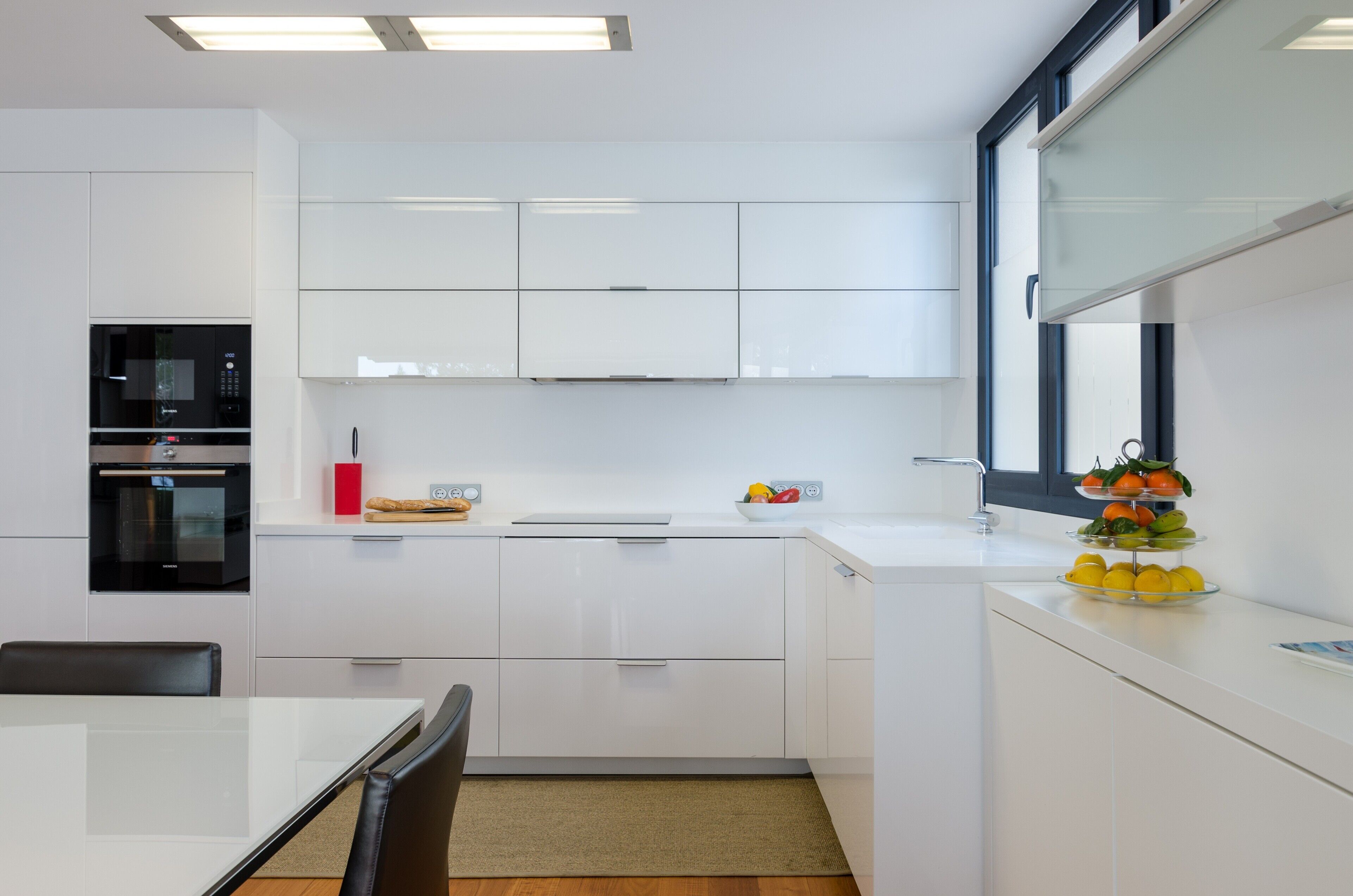 Eine moderne Küche mit weißen Schränken, einem eingebauten Backofen und einem Fenster.