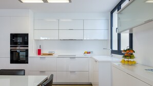 A modern kitchen with white cabinetry, a built-in oven, and a window. - PONENT - Modern apartment with sea views in Portocolom Free WiFi (Portocolom)