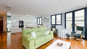 A modern living room with a green sofa, a white coffee table, and a dining area with a round table and chairs. - PONENT - Modern apartment with sea views in Portocolom Free WiFi (Portocolom)