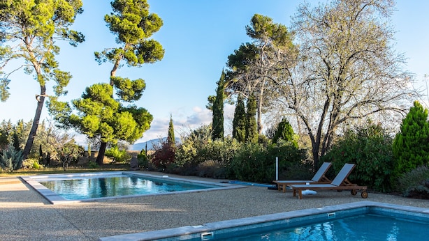 A pool area with two pools, surrounded by trees and a gravel path. - La Maison Vigneronne (Trebes)