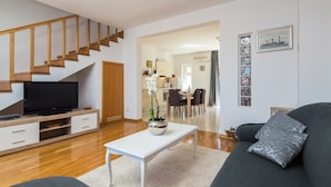 En moderne stue med fjernsyn, sofa, sofabord og trappe.