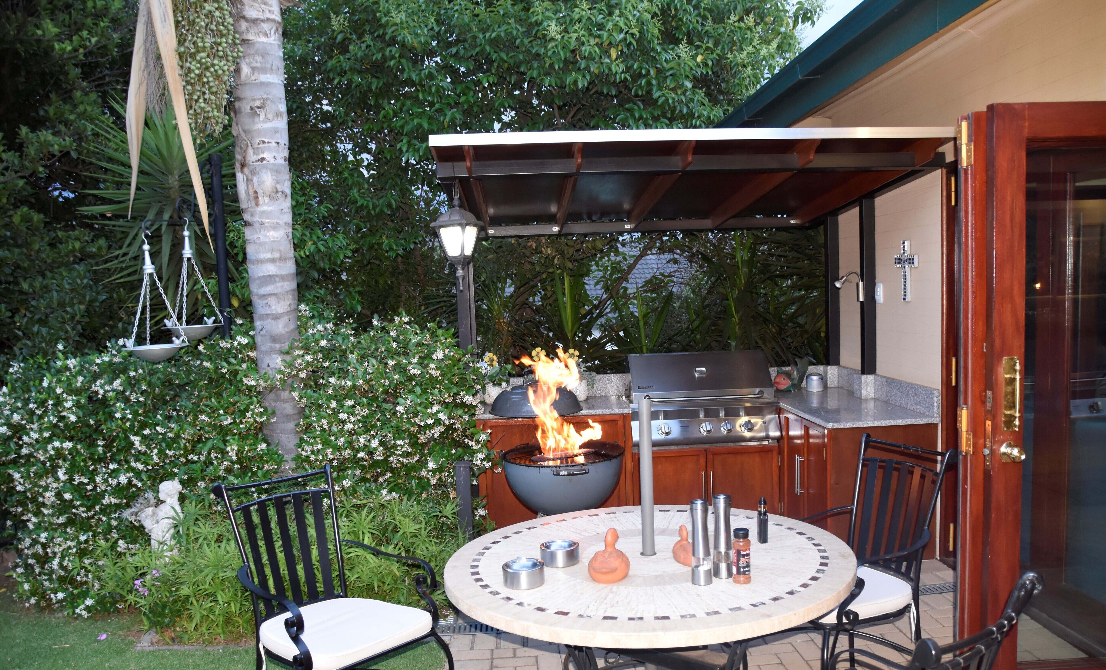 An outdoor patio with a round table, chairs, a grill, and a fire feature.