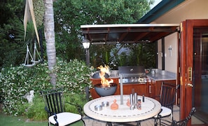 An outdoor patio with a round table, chairs, a grill, and a fire feature. - Lamor Guest House (Middelburg)