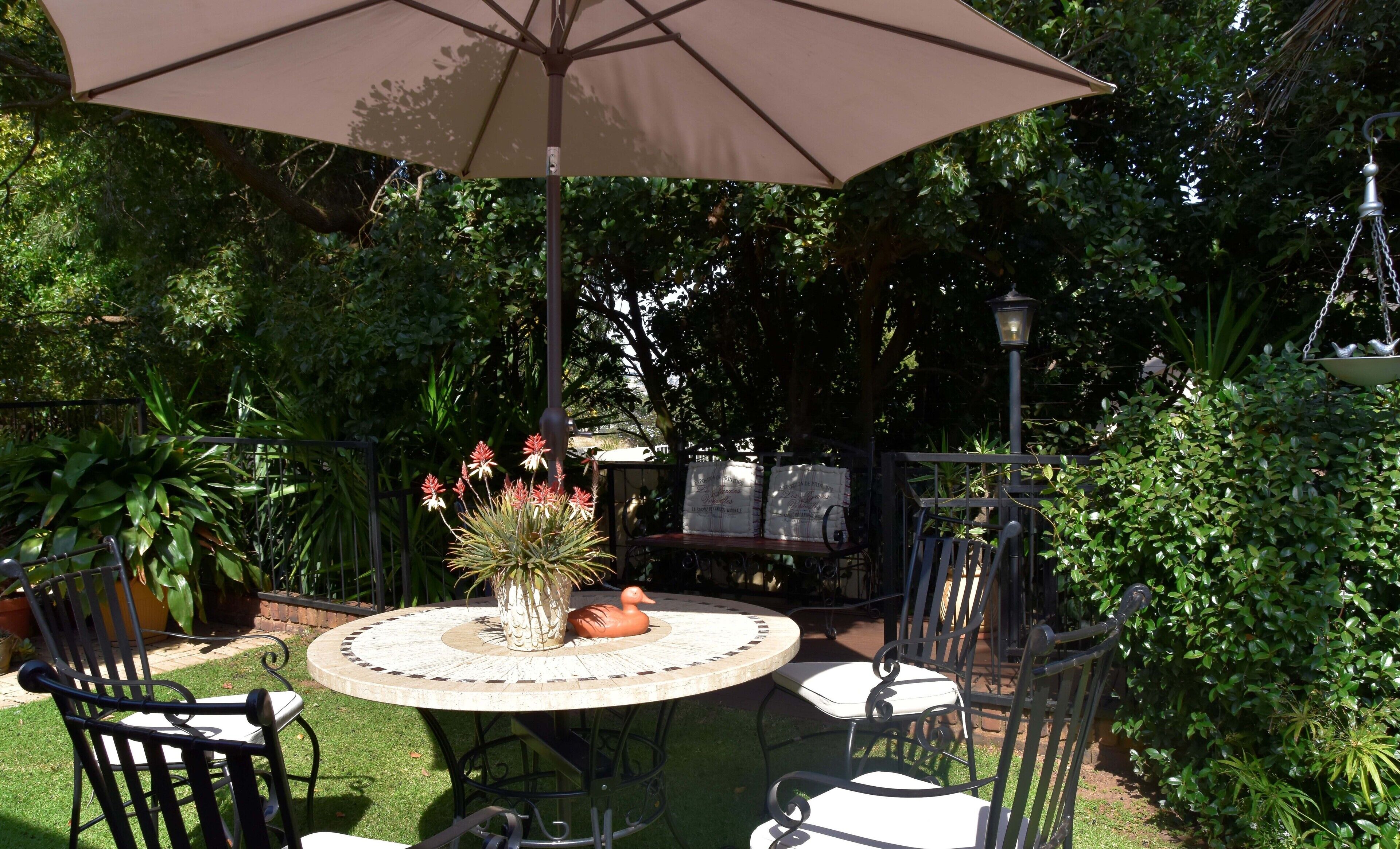 An outdoor patio with a round table, chairs, and an umbrella.