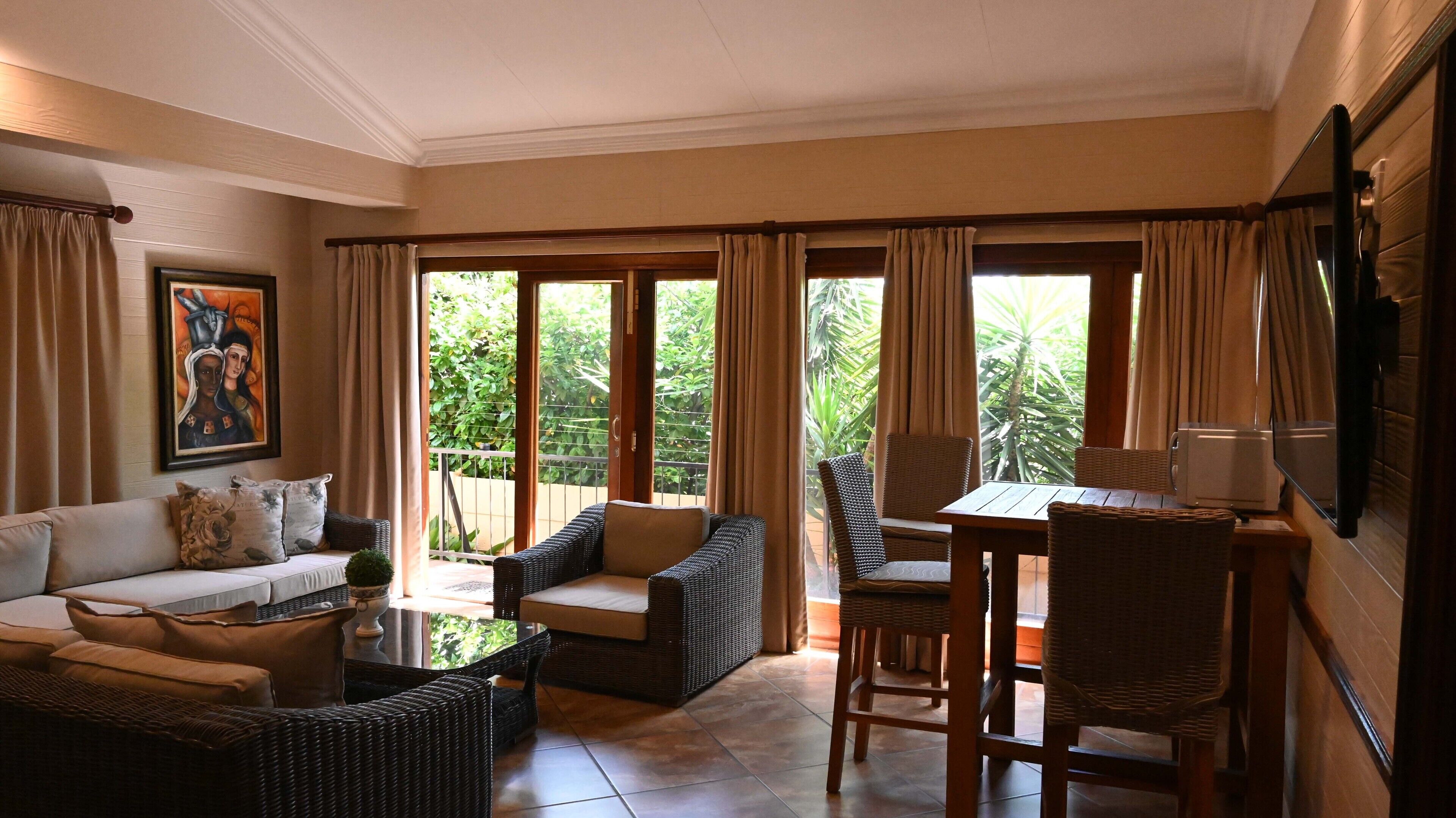 A spacious living room with a sofa, chairs, a table, and a TV.